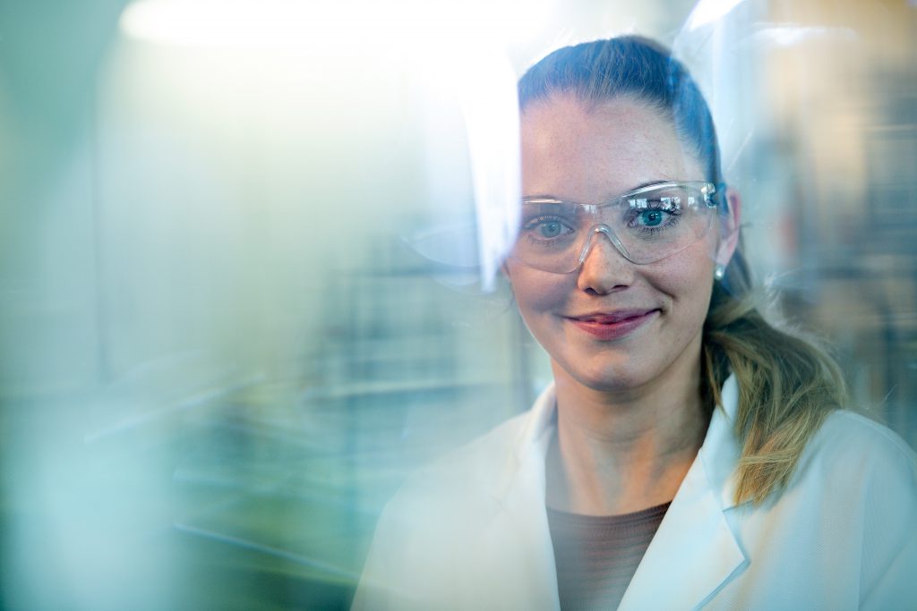 Eine Frau mit Schutzbrille und weißem Kittel